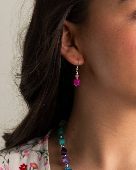 Woman wearing a colorful beaded necklace and earrings.