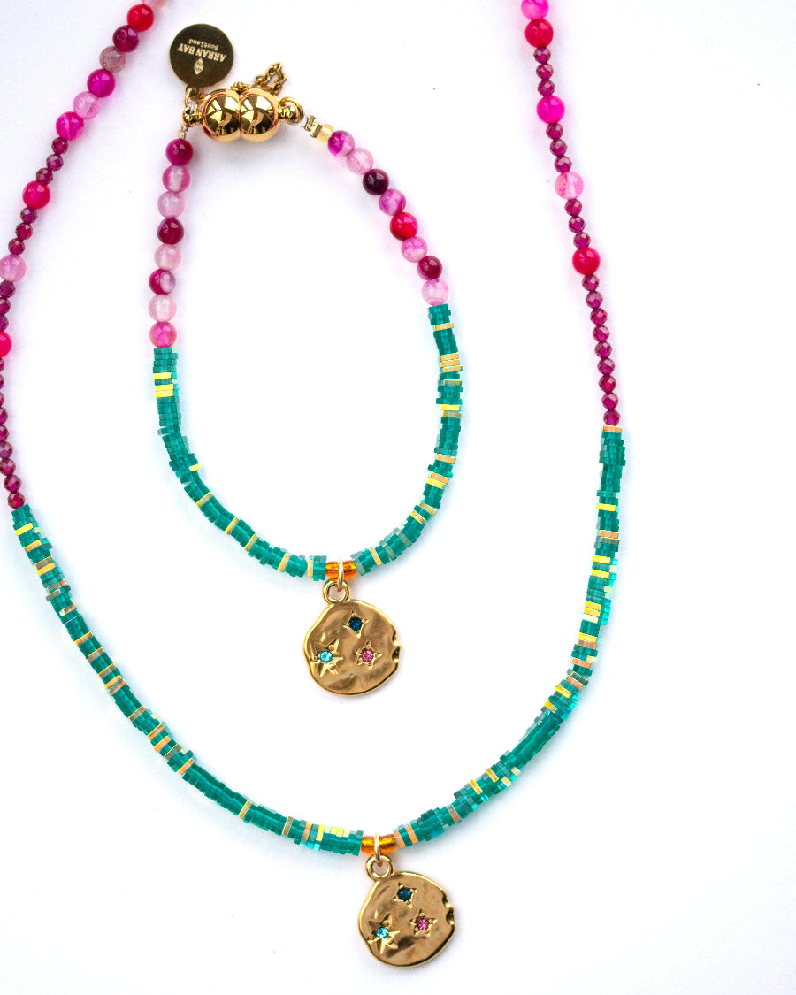 Two beaded teal necklaces with gold pendants, pink gemstones
