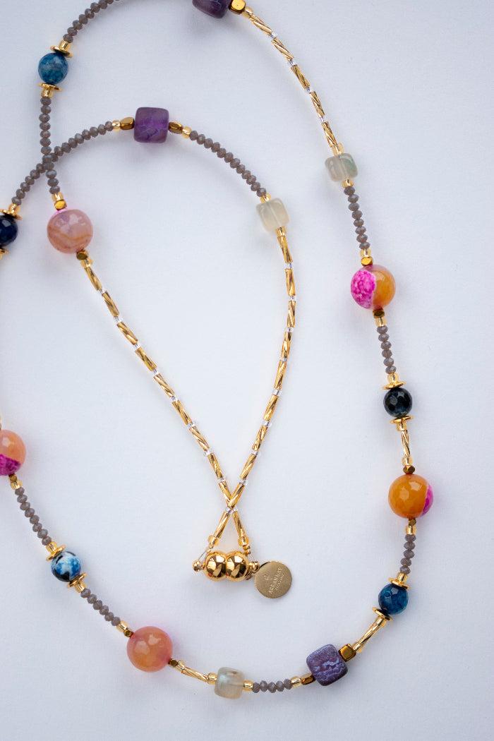 Multicolored beaded necklace with gold chain on a white background