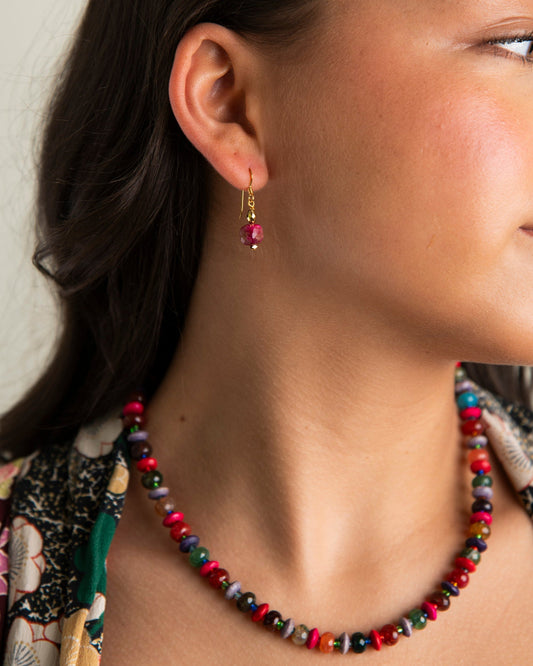 Close-up of a woman wearing a colorful beaded necklace and earrings.
